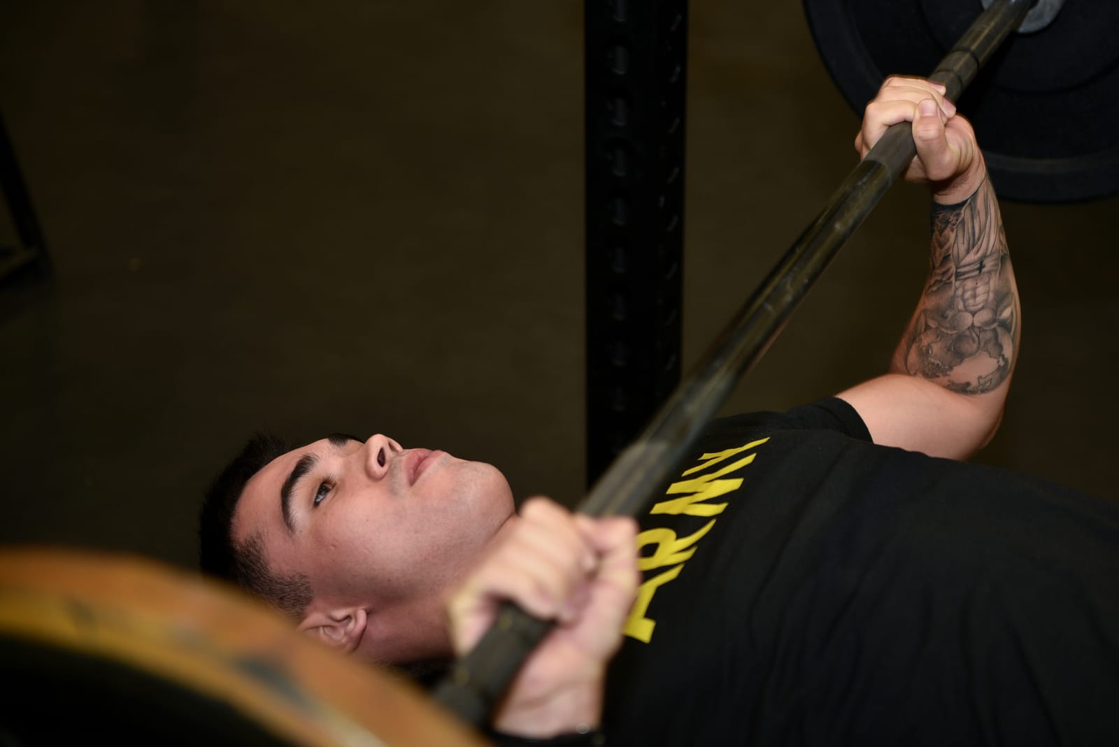 Photograph of a flat barbell bench press in mid-range, elbows tucked, no competitor watermark.