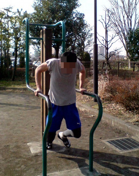 Outdoor parallel-bar dip at the bottom/mid-range with a forward lean.