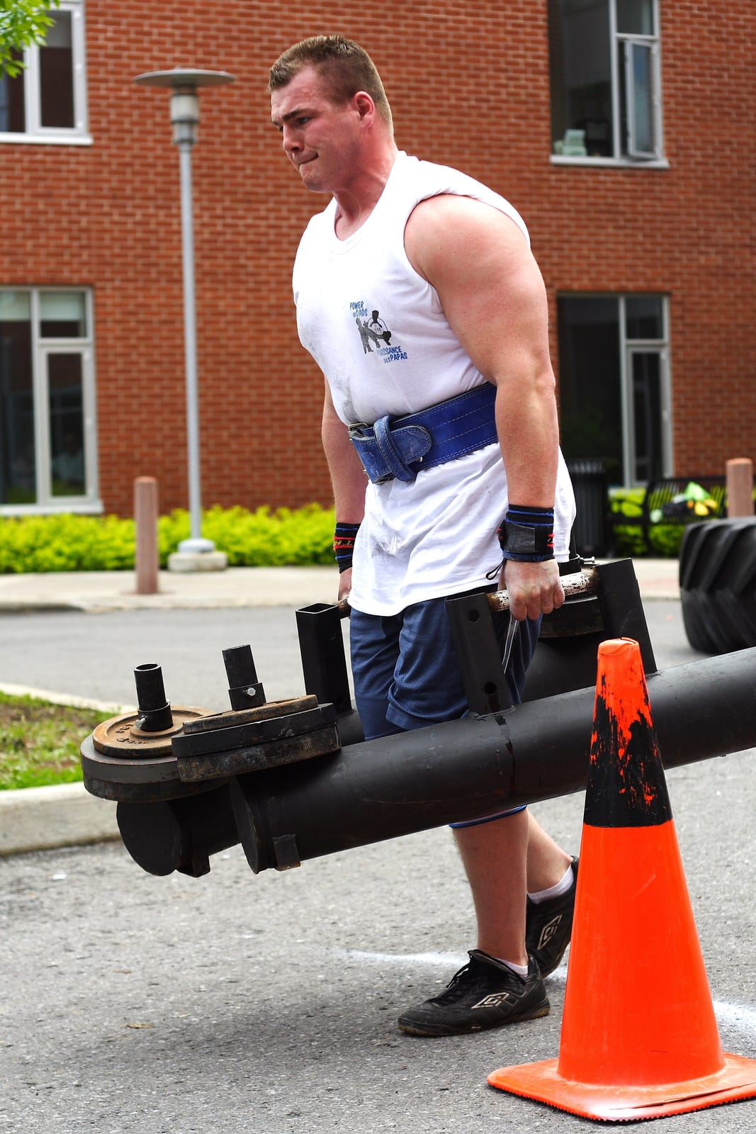 Mid-stride farmer carry with loaded handles, upright torso.