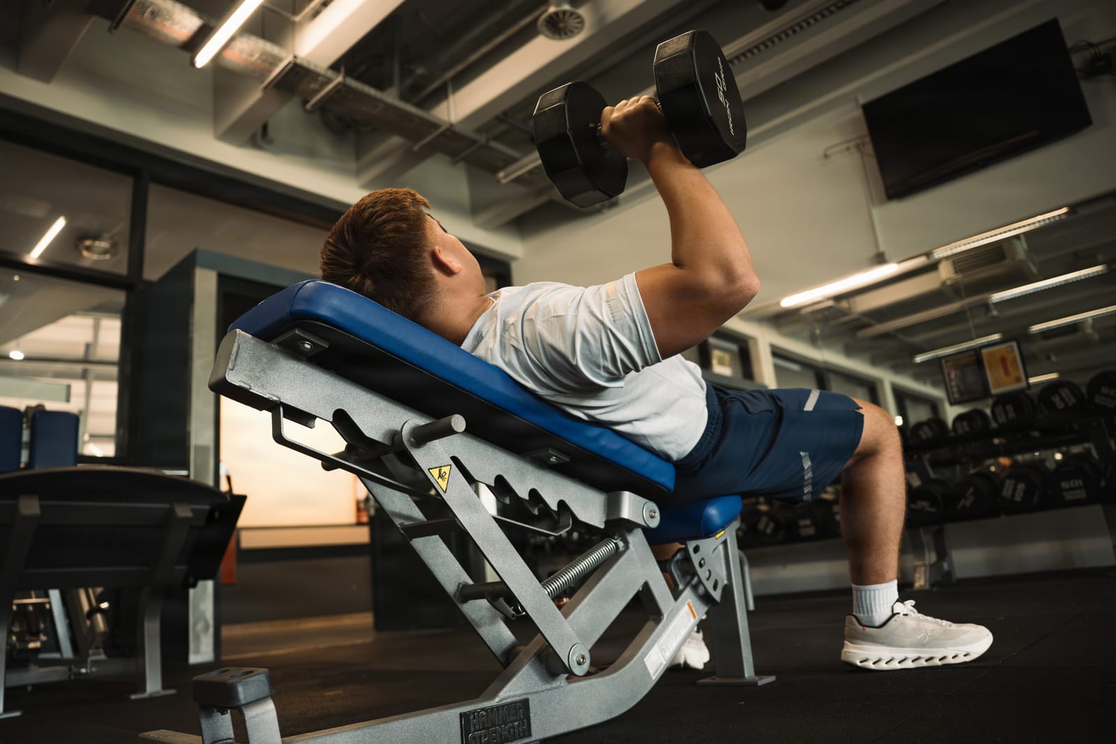 Side view of an incline dumbbell press at lockout.
